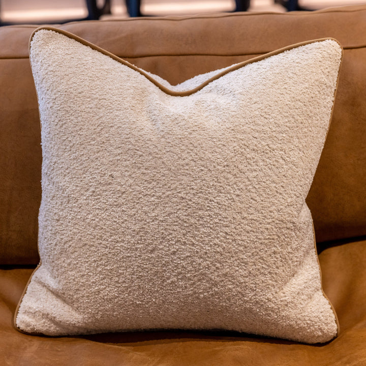 Luxury boucle cushion in ecru with a tan coloured piping. A plump feather inner cushion is included. Our made to order cushions are plump and cosy.  Dimensions: 500 x 500 mm  Made to order in approx 3 weeks